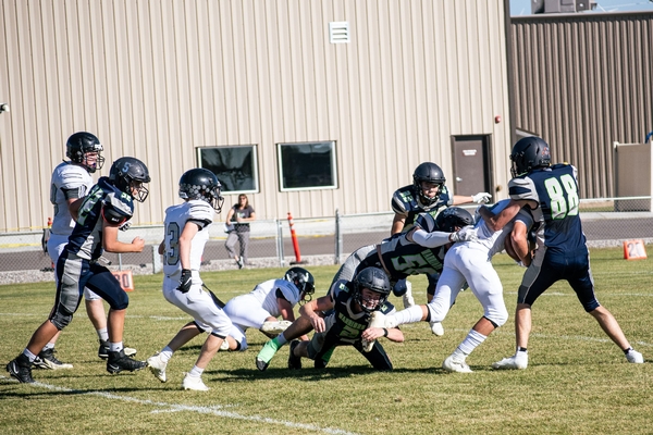 Football players tackling opposing team player.